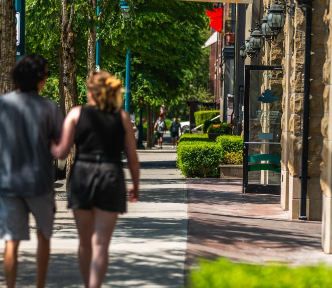 Two people walking down the street near businesses