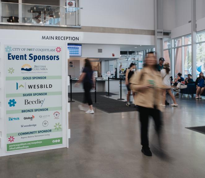 person walking by event sponsor signage at event