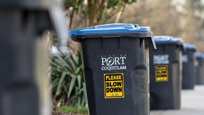 A row of garbage cans with please slow down signs on them