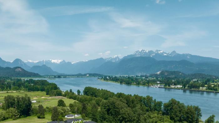 A view of a river with trees on either side and moutains in the background