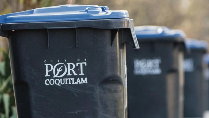 Lined up garbage cans on a street that say 'City of Port Coquitlam'