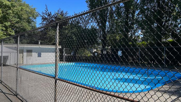 Outdoor pool behind a black chainlink fence.
