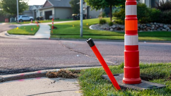 Fibre optic conduit marked with a construction cone.
