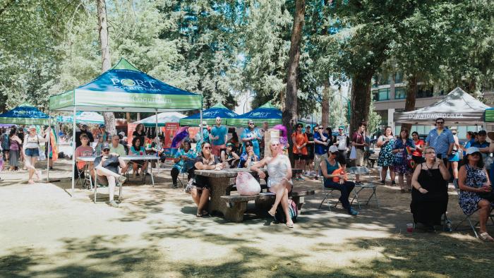 People celebrating Pride month in Lions Park sitting under pop-up tents and at picnic tables