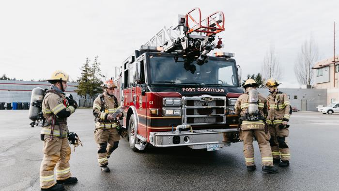 Four firefighters around a fire truck