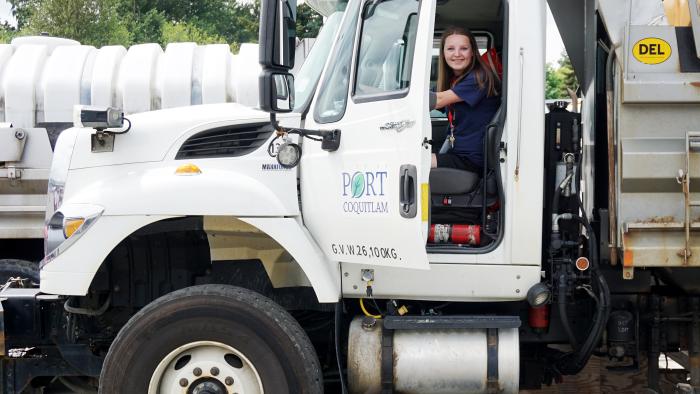 Woman driving municipal dump truck.