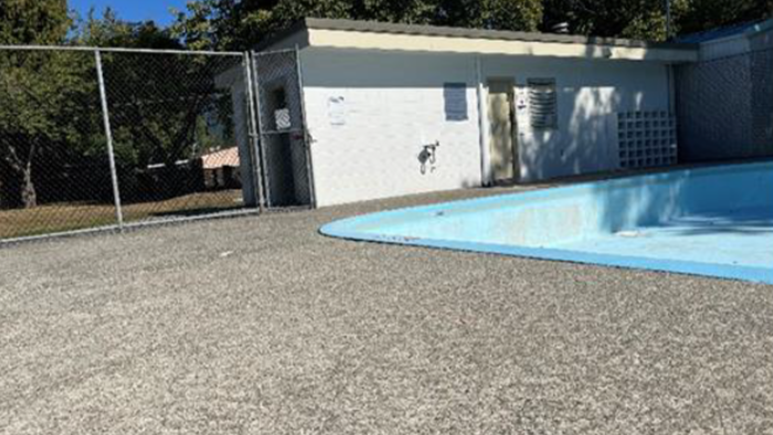 Empty outdoor pool. There is a chain-linked fence in the background.