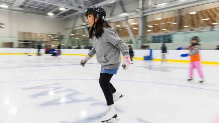 Young girl ice skating at indoor arena
