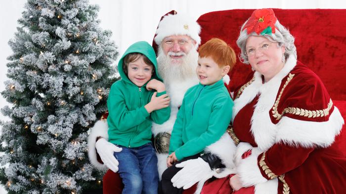 Two kids taking photos with Santa and Mrs. Claus