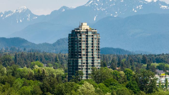 Tall apartment building surrounded by trees and mountains