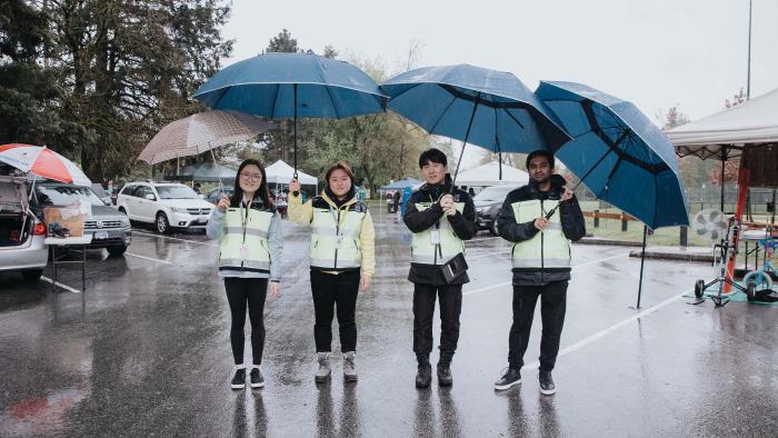 Four community police volunteering on a patrol standing under umbrellas