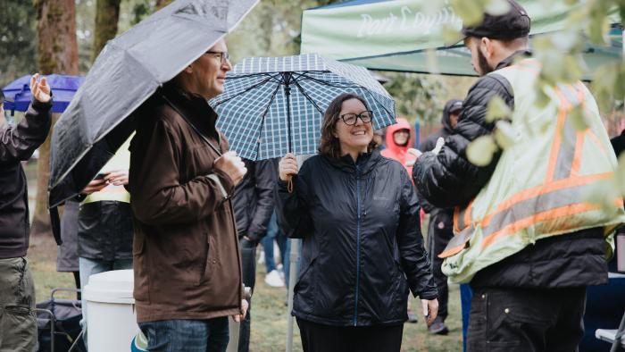 People under umbrellas in the park at Earth Day Event