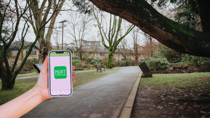 Holding up a phone with app displayed, nature pathway in the background