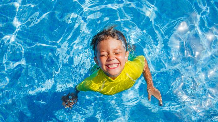Child smiling swimming in outdoor pool