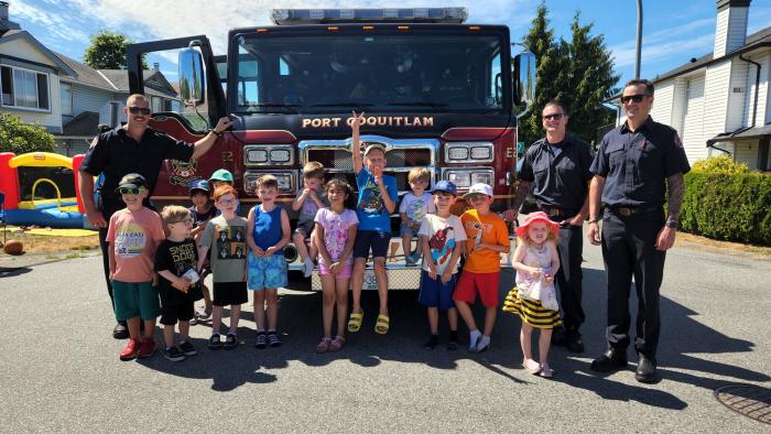 Kids at a block party gathered around a fire truck display