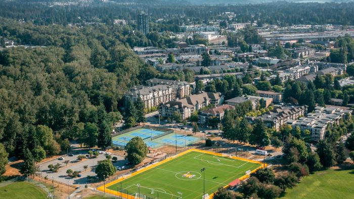 Drone view of Gates Park, with sport fields, courts, paths. Mountains and city in the distance