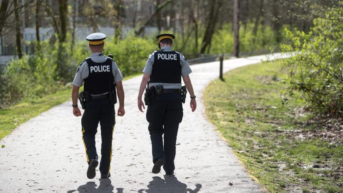 Two police officers walking down a trail