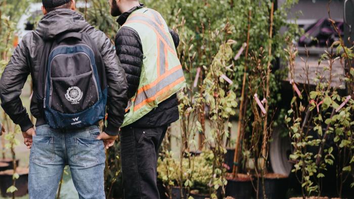 Resident and City staff member in high-vis vest looking trees