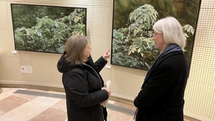 Two people standing in front of two pieces in art gallery