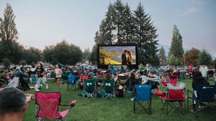 outdoor movie screen in the park with people gathered around