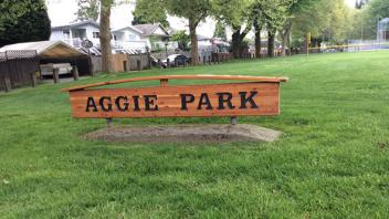 Signage for Aggie Park. The sign is wooden with dark letters.