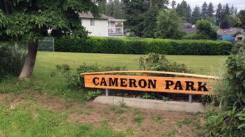Signage for Cameron Park. The sign is wooden with dark lettering.