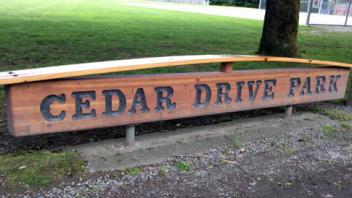 Signage for Cedar Drive Park. The sign is wooden with dark lettering.
