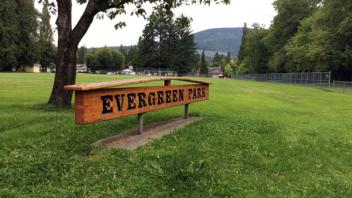 Signage for Evergreen Park. The sign is wooden with dark lettering.