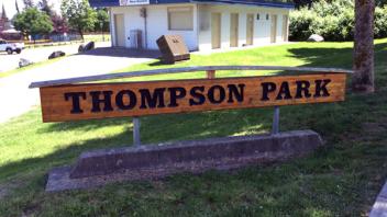 Thompson Park sign. The sign is wooden with dark lettering.