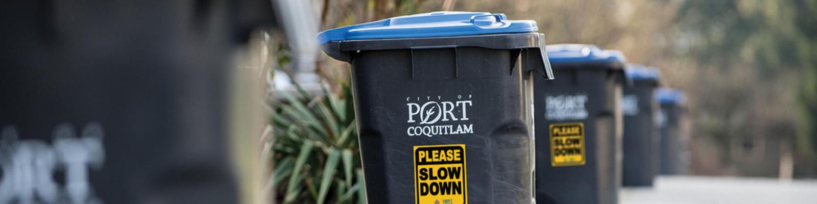 A row of garbage cans with please slow down signs on them