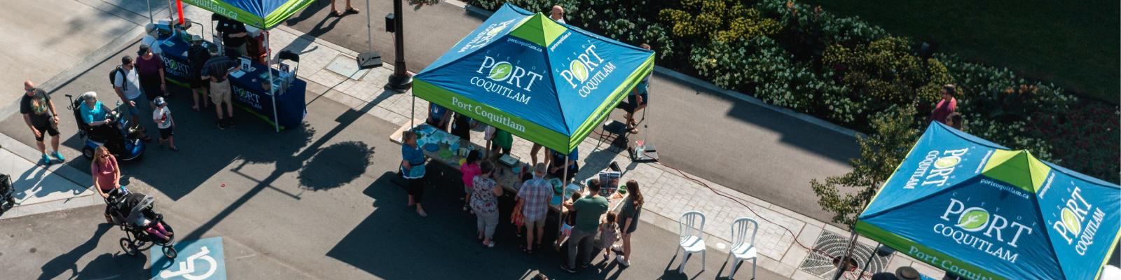 Aerial view of a street with tents that have Port Coquitlam's logo on them.