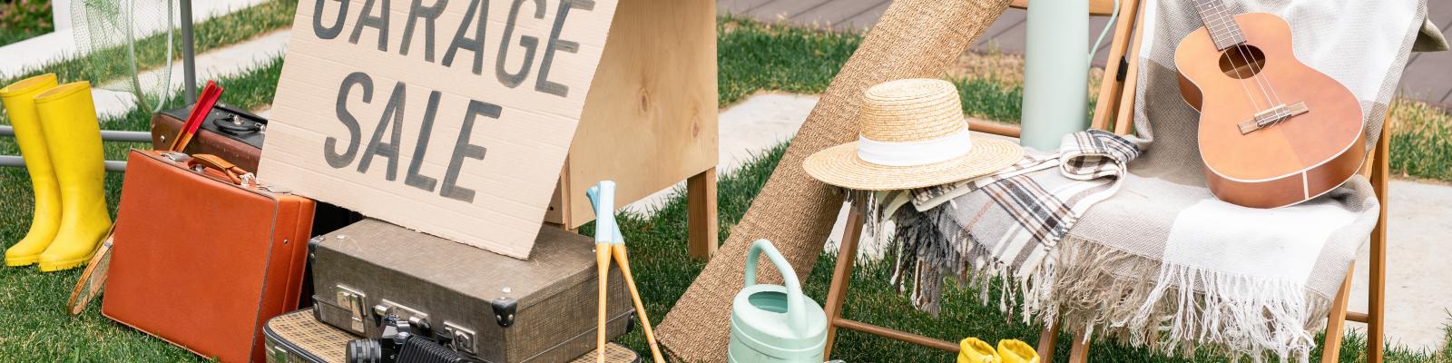 Garage sale set up in a yard with items for sale and a sign reading "garage sale"