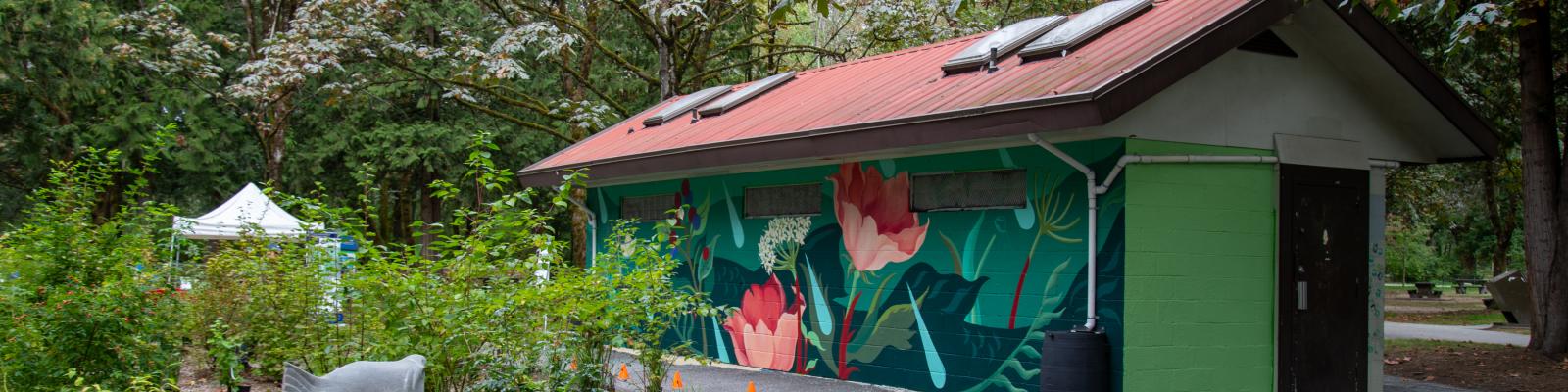 Fieldhouse studio at Lions Park with colourful painted mural and greenery surrounding