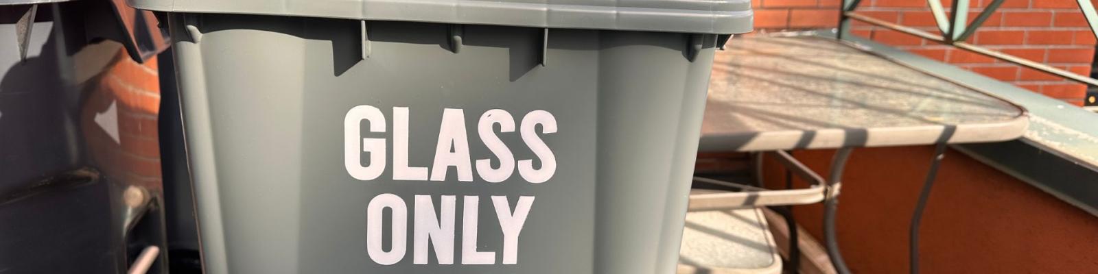 Person holding glass recycling bin outside