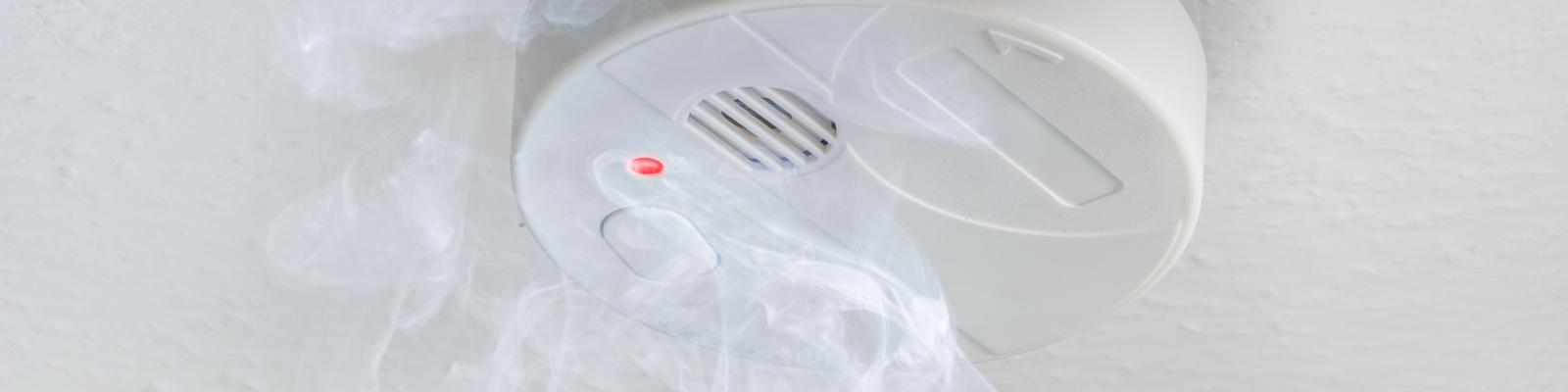Smoke alarm on ceiling with smoke surrounding