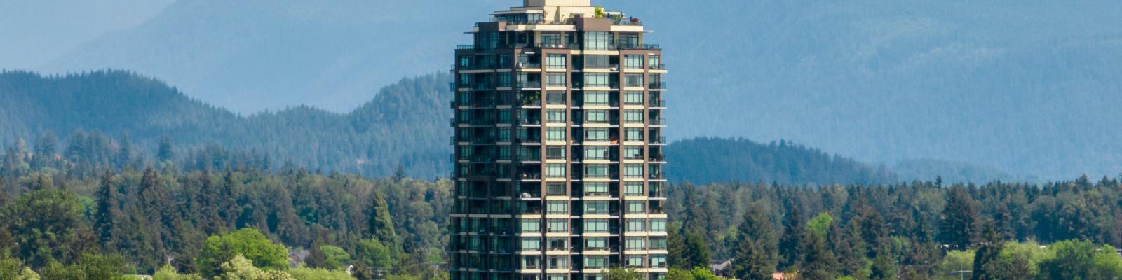Tall apartment building surrounded by trees and mountains