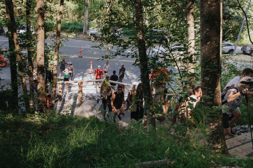 Crowd walking through heavily wooded area of a trail.