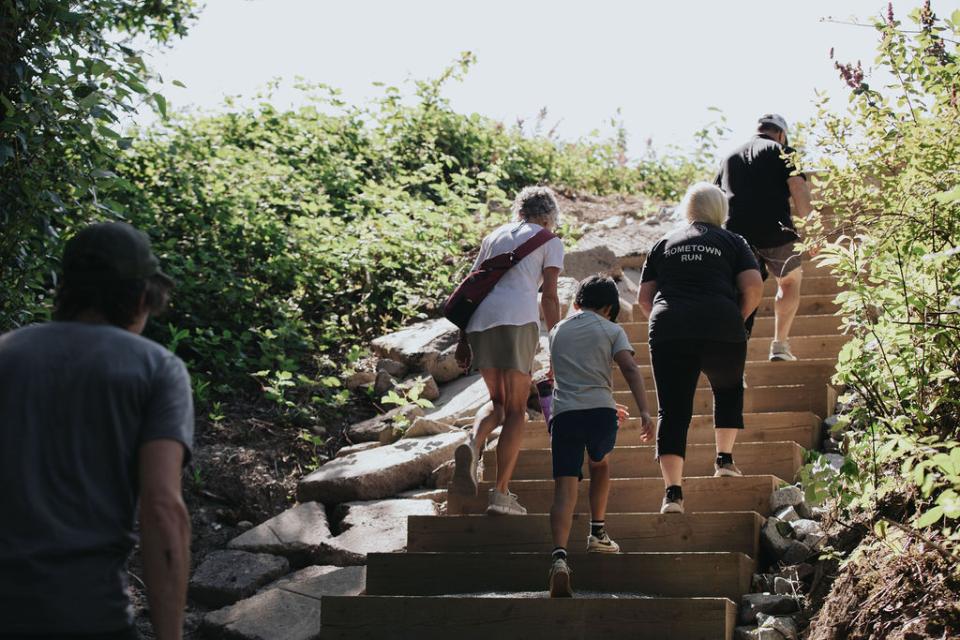 Crowd climbing concrete steps surrounded by shrubs and greenery.