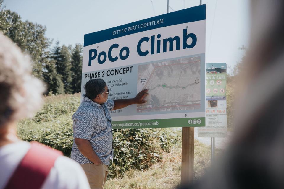 Person pointing at PoCo Climb phase two sign.