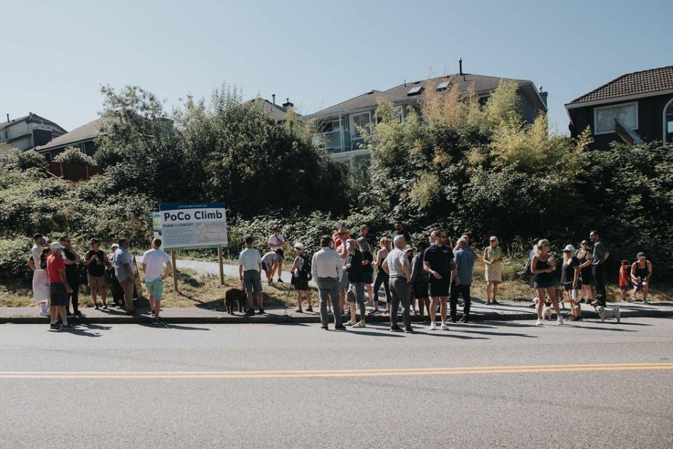 Crowd gathered outside near a PoCo Climb project phase sign.