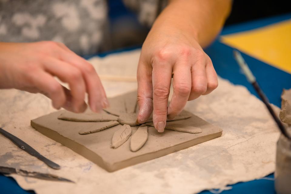 An unpainted clay tile with a daisy