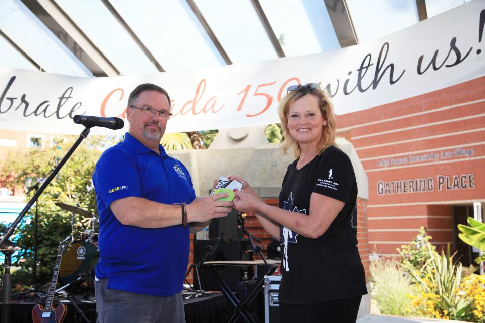 Two people on a stage exchanging gifts