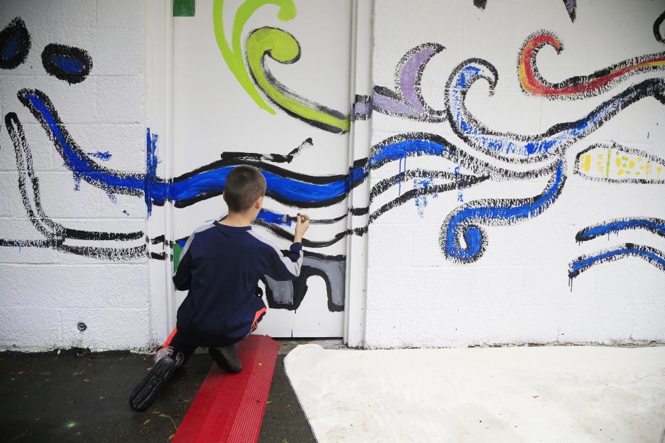 A child working on a wall mural