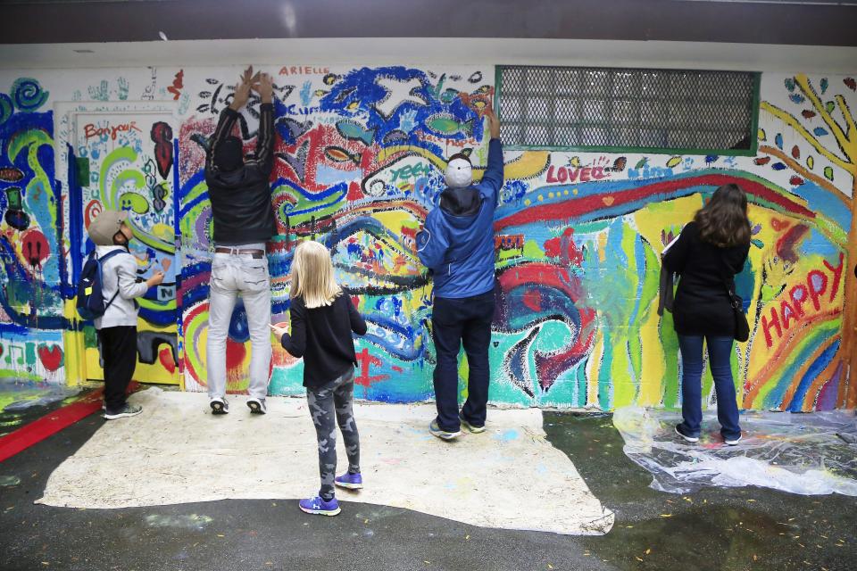 Several people working on a wall mural