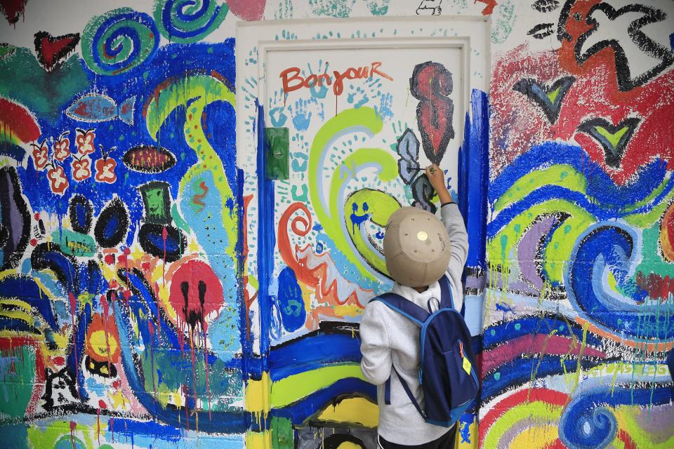A person mainting a colourful mural wall
