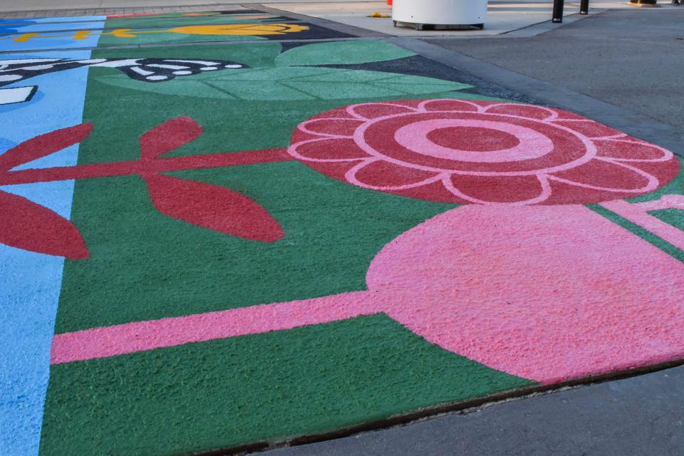 A sidewalk mural featuring various coloured flowers