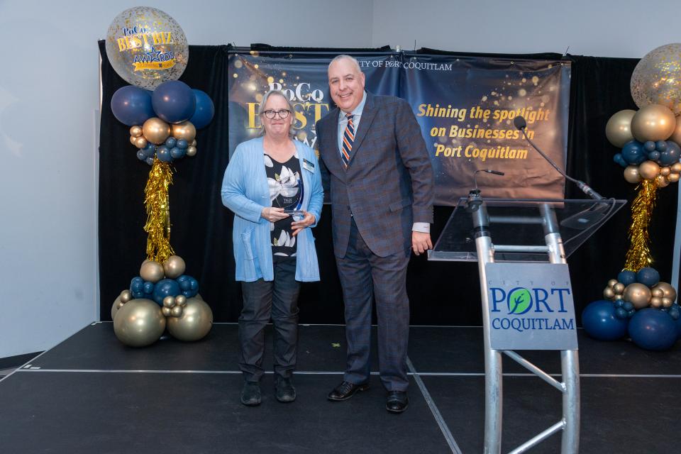 Small business of the year award winner standing on stage at with award at Best Biz event