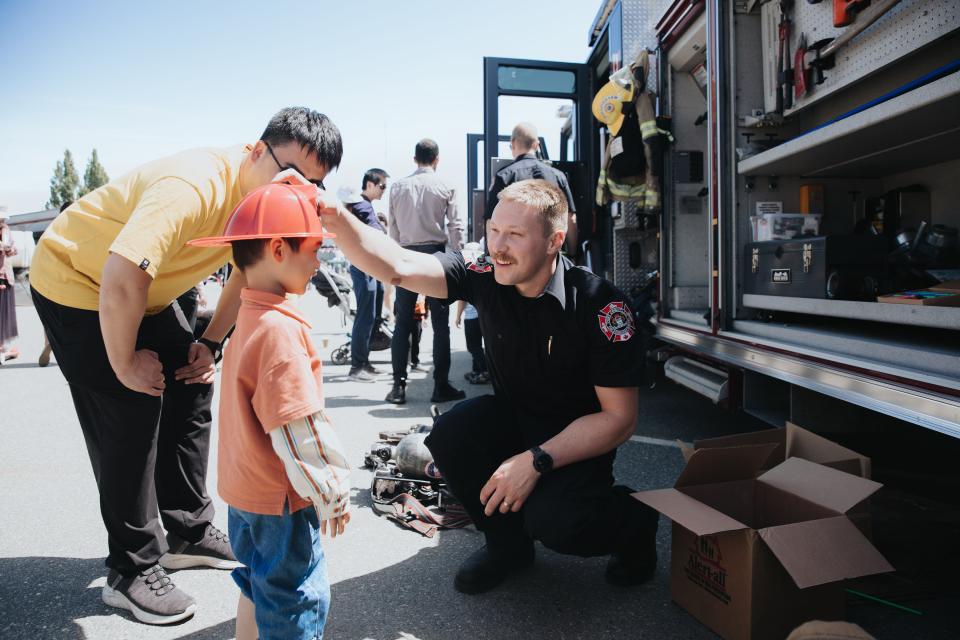 Kid meeting firefighter in front of fire truck at Public Works Open House