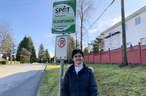 A woman standing next to a no parking sign in a naighbourhood