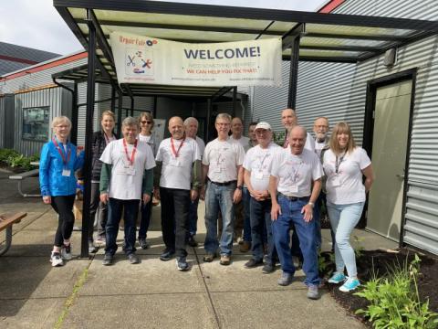 A group of people standing outside the repair cafe sign
